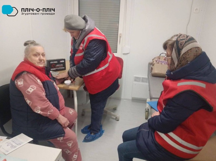 Фахівці Червоного Хреста міряють тиск жінці похилого віку