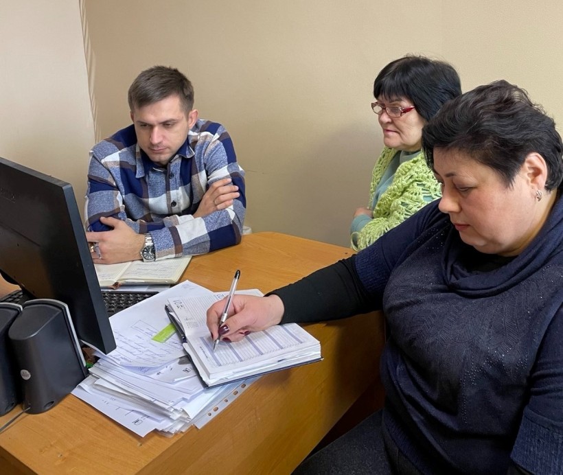 Представники військової адміністрації сидять за столом та слухають доповідача на семінарі