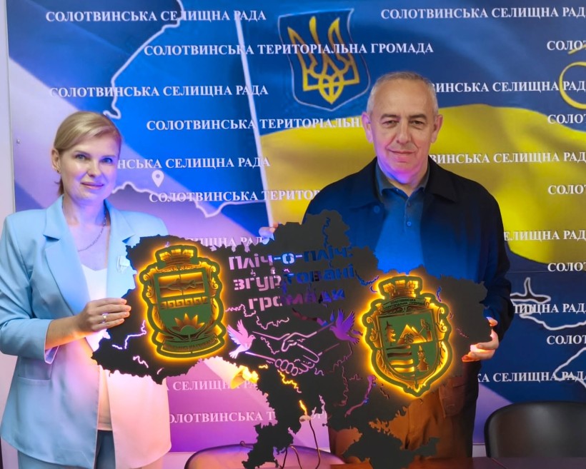 Начальник Мангушської селищної військової адміністрації наталя Воробйова передає голові Солотвинської громади символічну карту