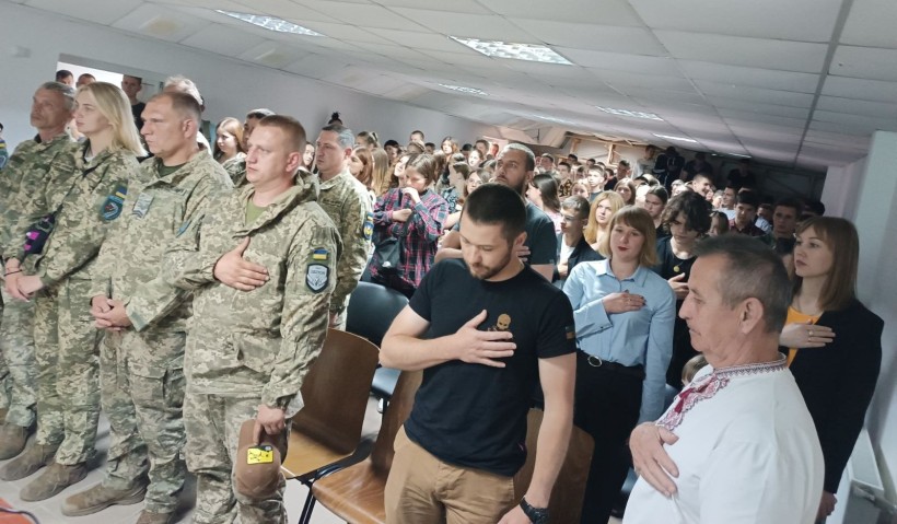 Гімн України звучить у залі, де разом із військовими стоять учні та педагоги. Символ єдності поколінь, гідності та незламності Донеччини.