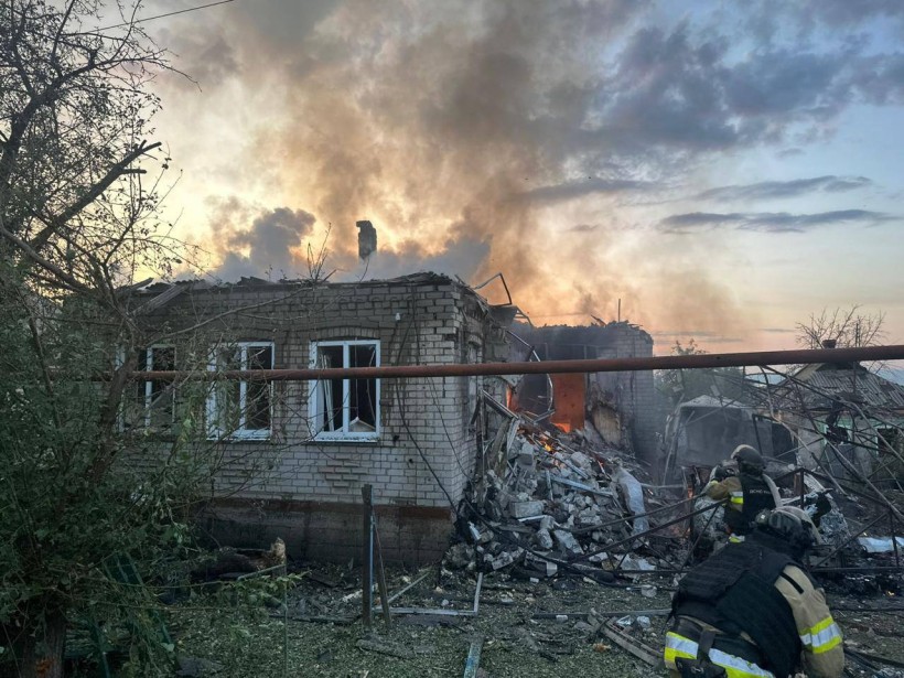 Рятувальник біля будівлі, яку зруйнували окупанти, гасить пожежу