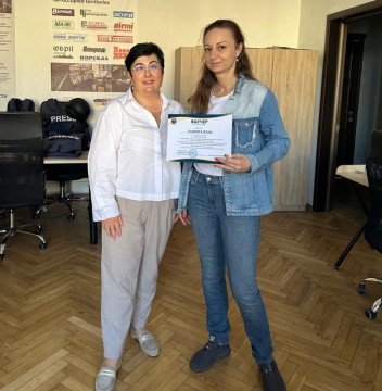 Наталія Адамова вручає Юлії Паніній ваучери на проходження навчання