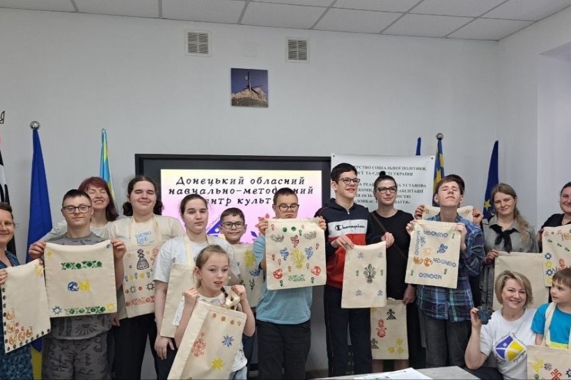 Спільне фото організаторів та учасників заходу, які  тримають перед собою розписані власноруч екосумки