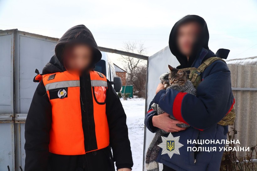 Евакуація населення. Дівчина стоїть у помаранчевому бронежилеті, поруч хлопець,який тримає у руках кота.