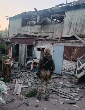 Правоохоронець стоїть біля зруйнованої будівлі