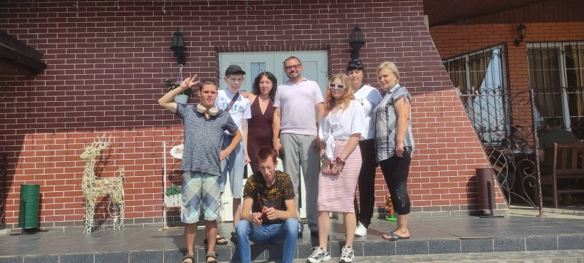 Учасники заходу, включаючи організаторів та дітей, позують для групового фото на фоні готельно-ресторанного комплексу «Застава».