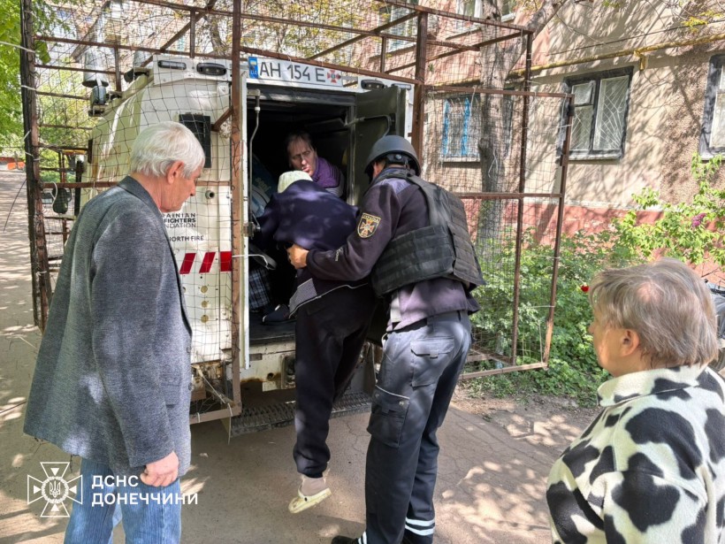 Рятувальники допомагають літній жінці сісти в евакуаційний автомобіль
