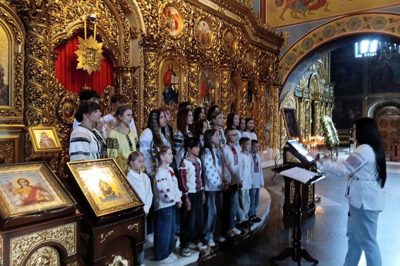 Дитячий хор у вишиванках співає в храмі біля іконостаса під керівництвом диригентки.