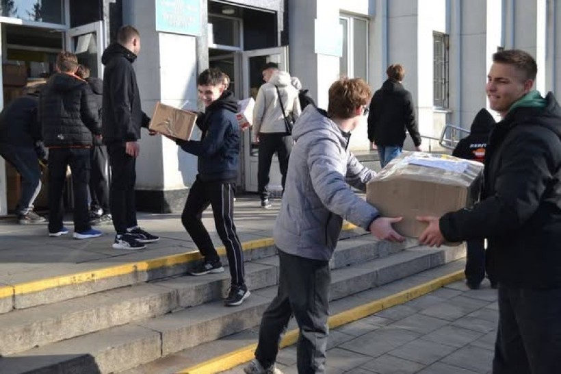 Молодь заносить коробки з гуманітарною допомогою