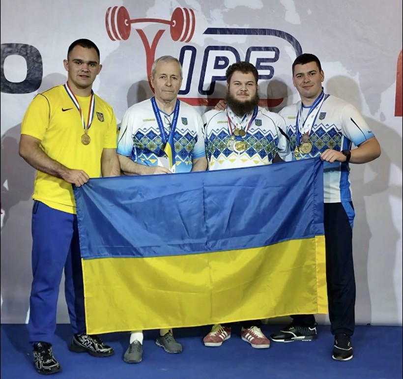 Українські спортсмени та тренери з медалями тримають прапор України