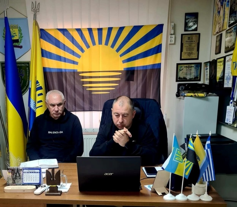 Начальник Сартанської селищної військової адміністрації Олександр Куркчи  та  заступник начальника управління - начальник відділу містобудування управління містобудування та архітектури Донецької облдержадміністрації Іван Оліфіровський.
Сидять біля монітора та обговорюють питання про розуміння безбар’єрності. Позаду них прапор Донеччини.