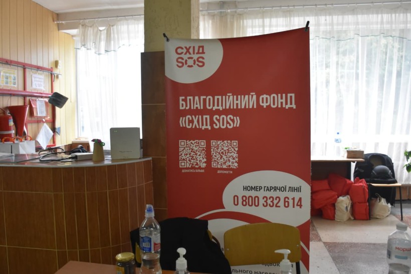 Банер з назвою благодійної організації на червоному фоні білими буквами написано "Схід SOS".