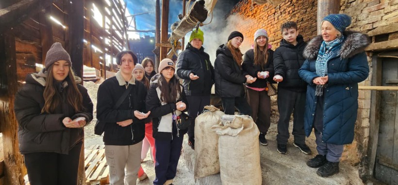 Спільне фото дітей на солеварні, у руках вони тримають сіль, поруч стоїть сіль у мішках.