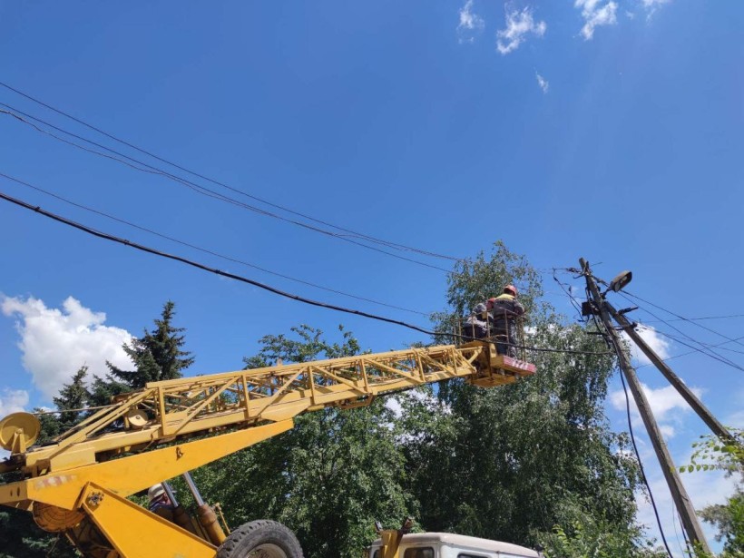 Електромонтери на підйомнику працюють з пошкодженими під час ворожого обстрілу електроопорами.