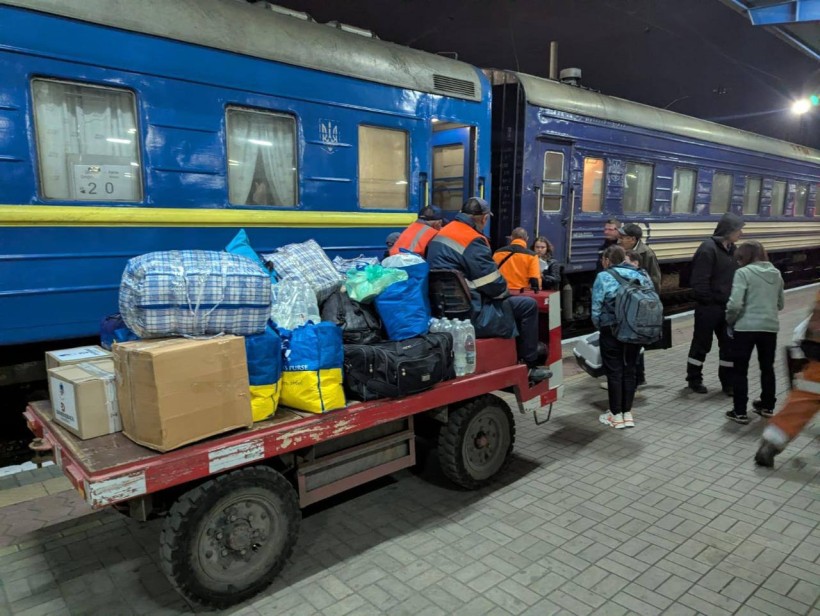 Люди з речами, наплічниками чекають на пероні посадку до потяга, на спеціальній платформі привезли торби людей
