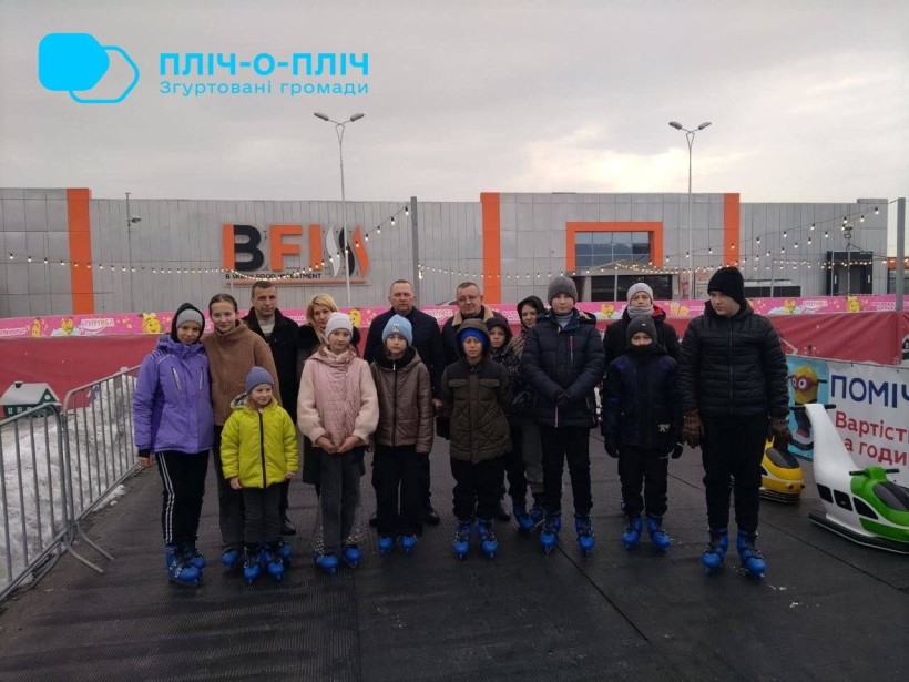 Спільне фото. Діти та дорослі стоять на ковзанах.