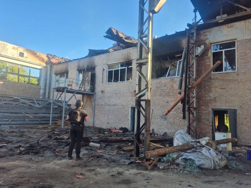 Правоохоронець стоїть біля зруйнованої окупантами будівлі