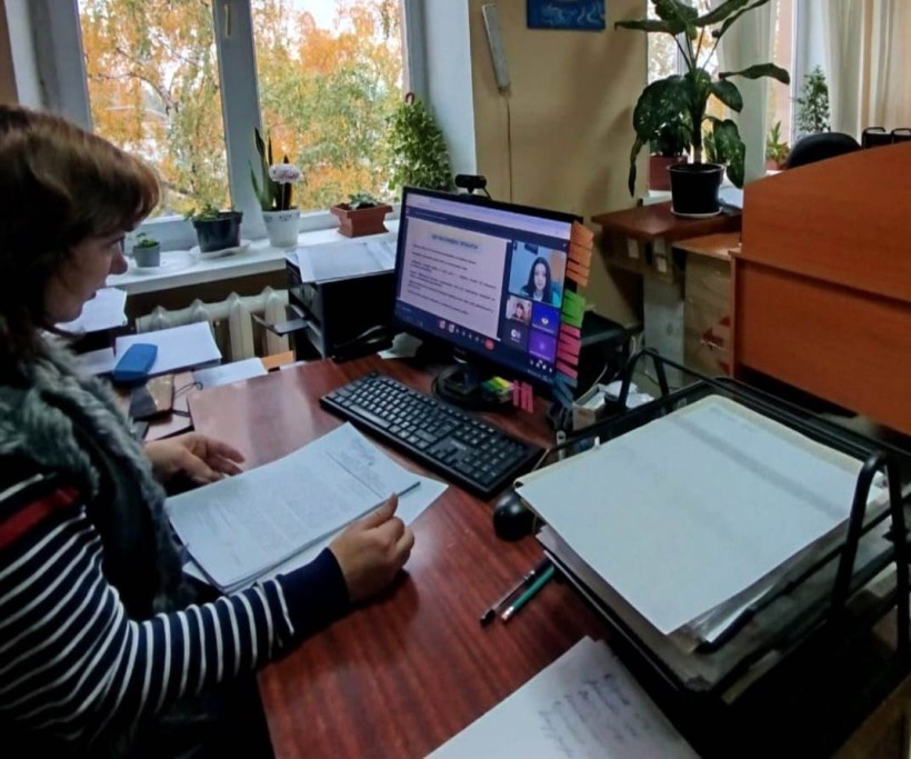 Представник військової адміністрації сидить за столом та слухає доповідача на семінарі