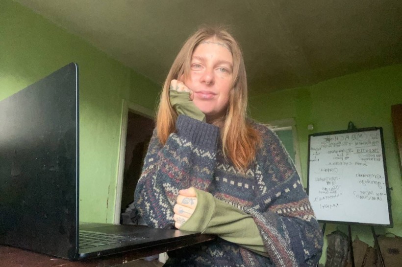 Бойова медикиня з позивним «Гайка» сидить перед ноутбуком у кімнаті