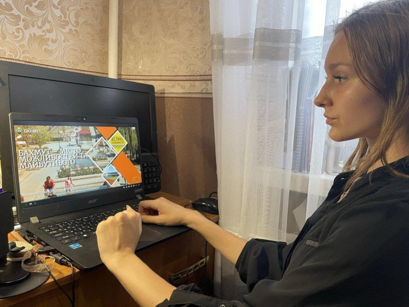 Дівчина за ноутбуком перегдядає відеоролик про Бахмут.