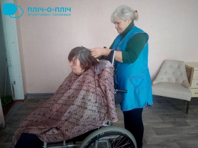 Фахівчиня Центру надання соціальних послуг Ружинської громади робить стрижку жінці в кріслі колісному