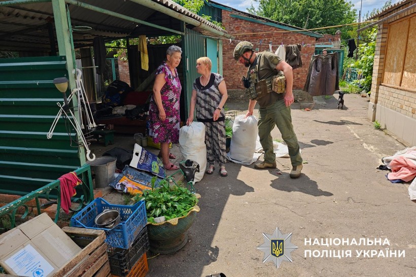 Поліцейський допомогає літнім жінкам зібрати речі першої необхідності для евакуації