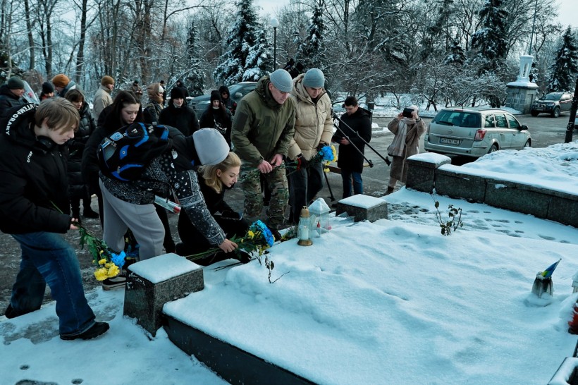 Учасники акції на Аскольдовій могилі покладають квіти до пам'ятника  Героїв Крут