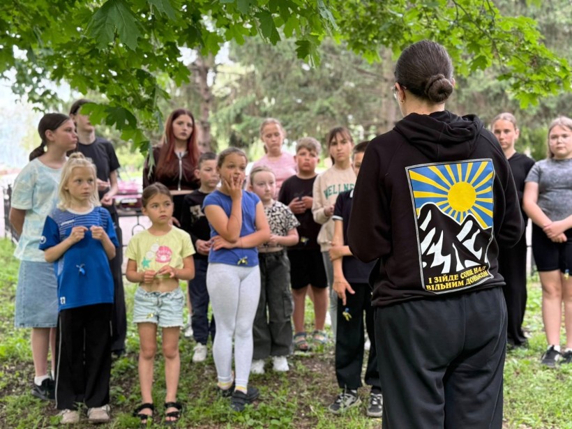 Діти та молодь Хлібодарівської громади слухають наставницю під час меморіального заходу