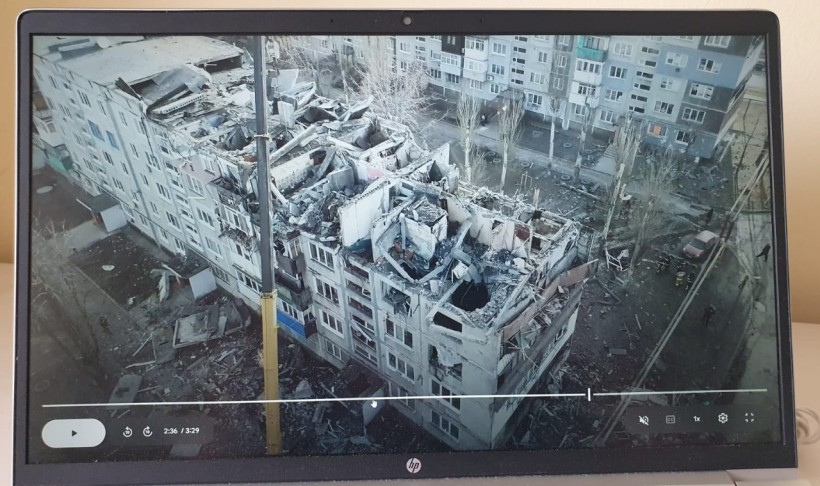 На екрані телевізора фотографія будинку після обстрілу.