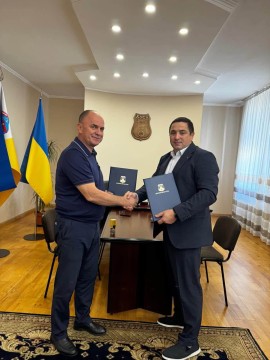 Начальник Микільської селищної військової адміністрації Володимир Халабузар та в.о. Хустського міського голови Василь Губаль тримають підписаний меморандум та тиснуть один одному руки