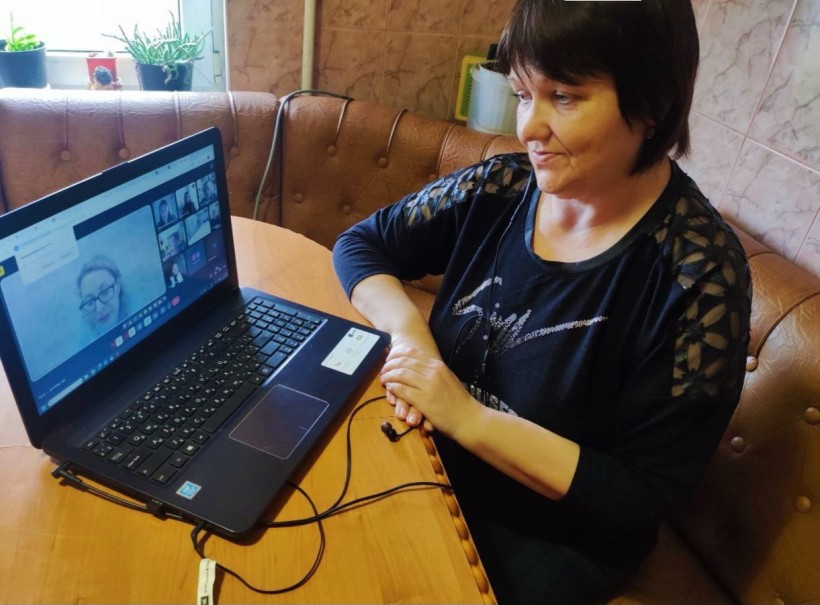 Представник військової адміністрації сидить за столом та слухає доповідача на семінарі