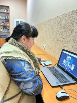 Бібліотекарка з ноутбуком бере участь в онлайновій зустрічі з колегами