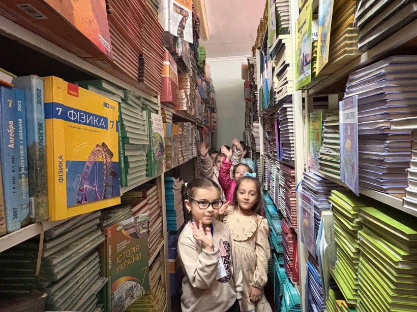 ДІти стоять між книжковими стелажами