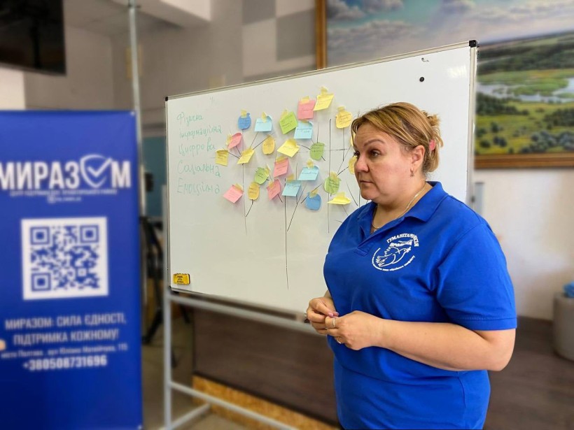 Працівниця "Проліски" стоїть перед білою дошкою зі стікерами в центрі "Миразом"