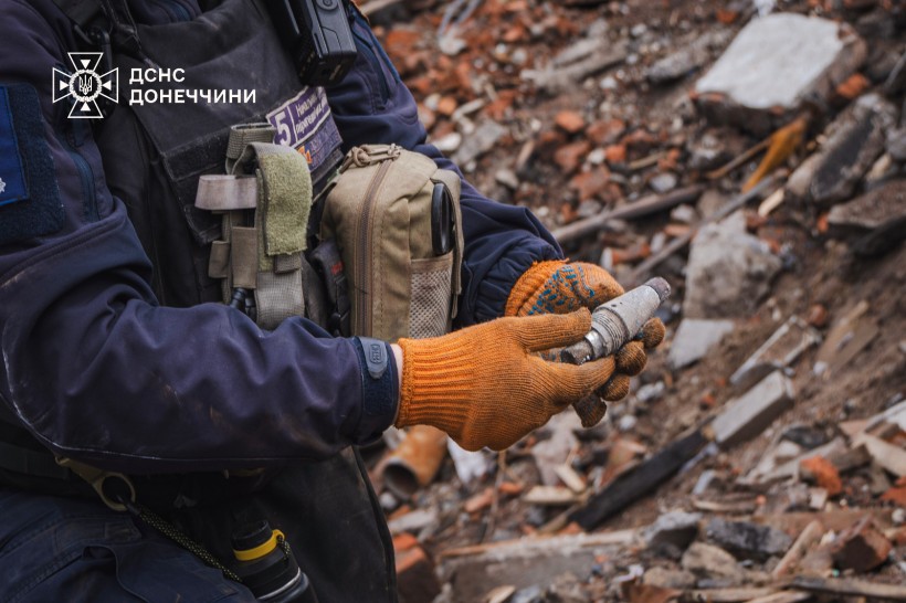 Збільшене фото. Піротехник тримає уламок снаряду.