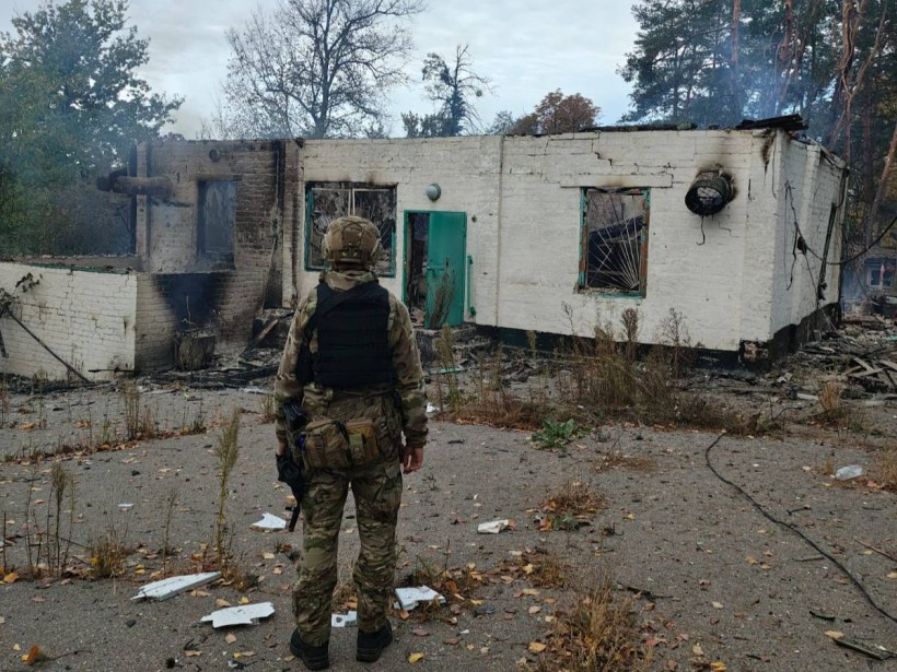 Правоохоронець стоїть біля обгорілого будинку