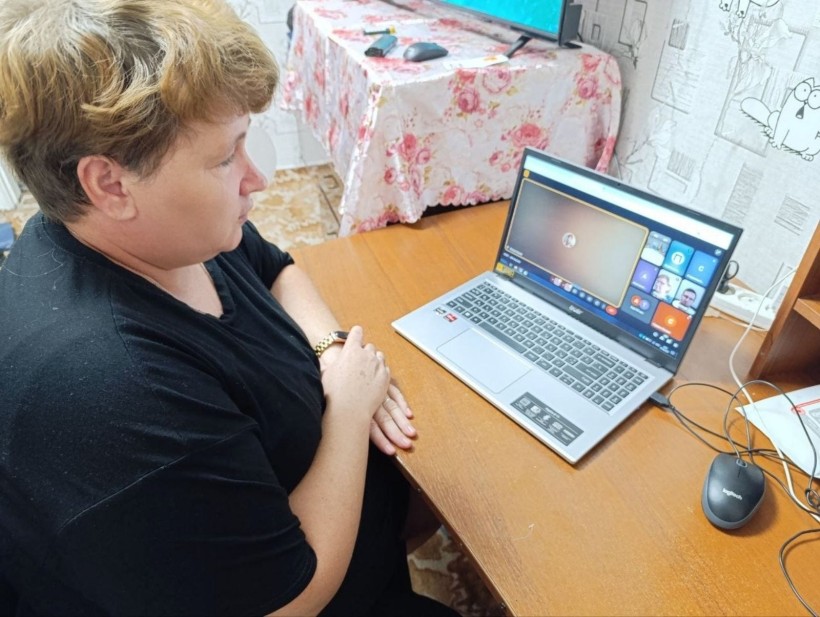 Представник військової адміністрації сидить за столом та слухає доповідача на семінарі