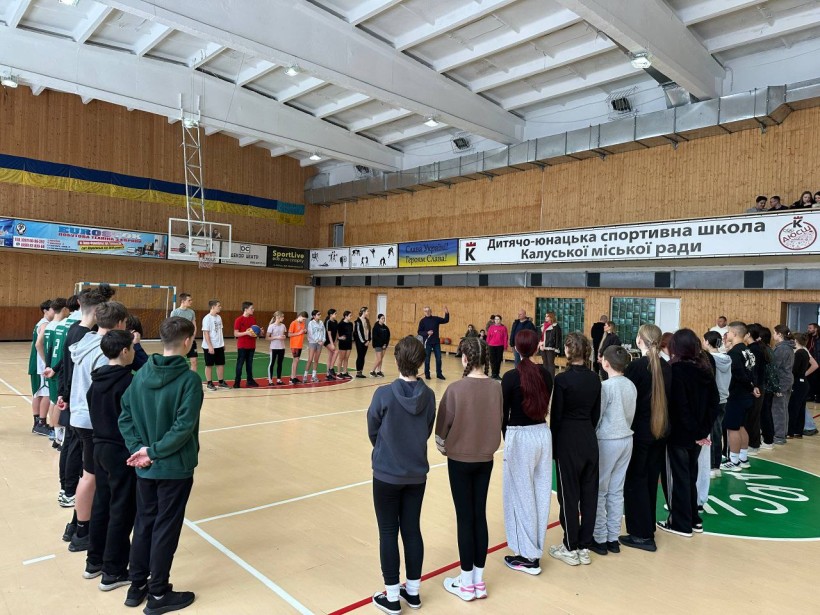 Дія у спортивному залі.
Учасники спортивних змагань стоять по середині залу, тренер розповідає правила участі.