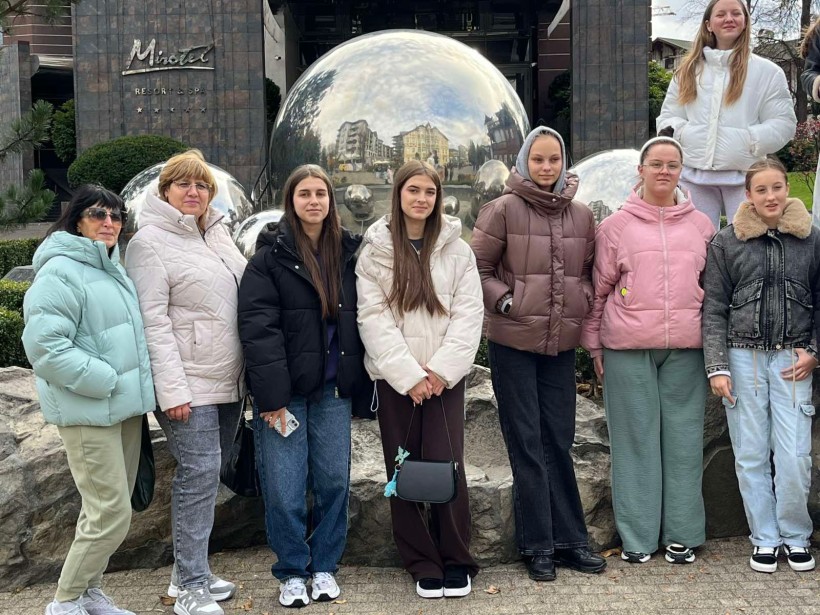 Учні Соледарської громади біля фасаду гостинці, позаду них дзеркальна куля.