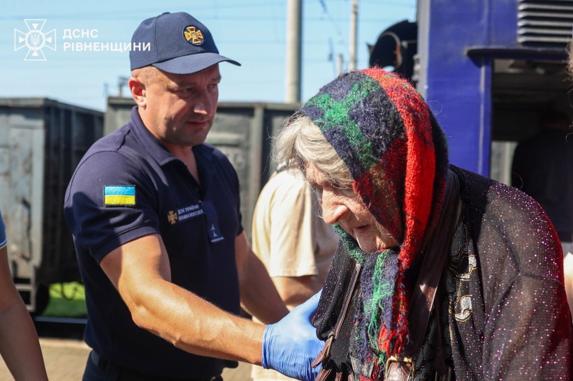 Представник ДСНС допомагає на пероні  літній жінці, яка була евакуйована з Донеччини
