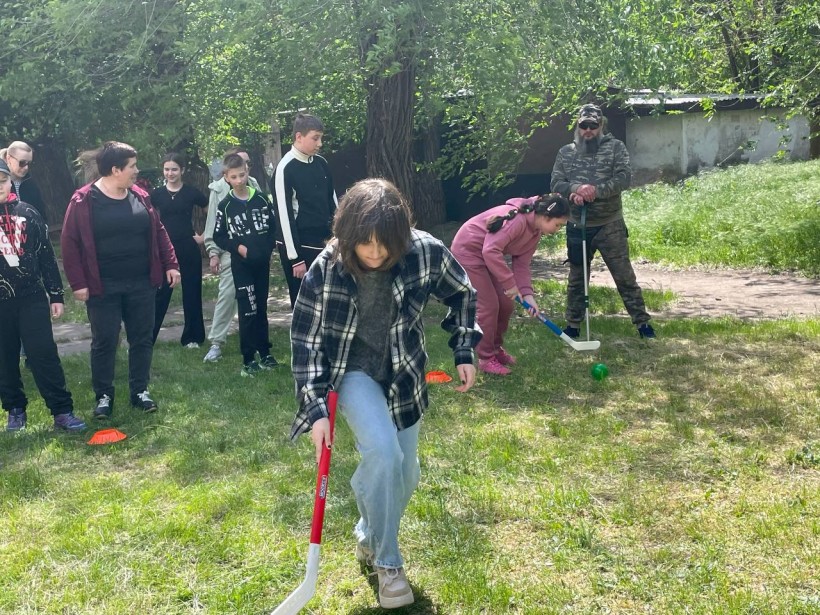 Група підлітків та дорослих разом з ветераном грають у спортивні ігри на галявині