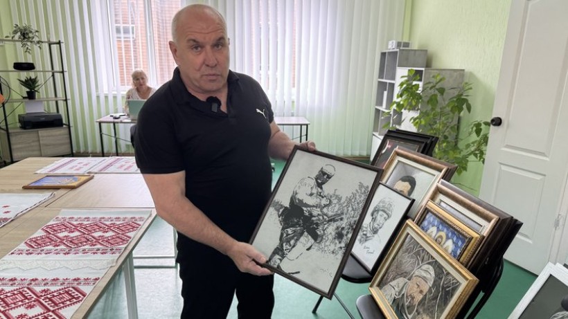 К. Діденко тримає роботу, на якій зображений воїн- герой Ігор Прокопенко