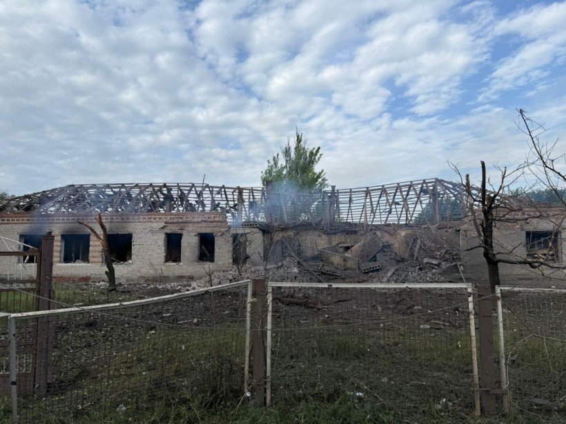 Складське приміщення, яке було зруйноване по центру ворожим обстрілом та паркан поруч з будівлею.
