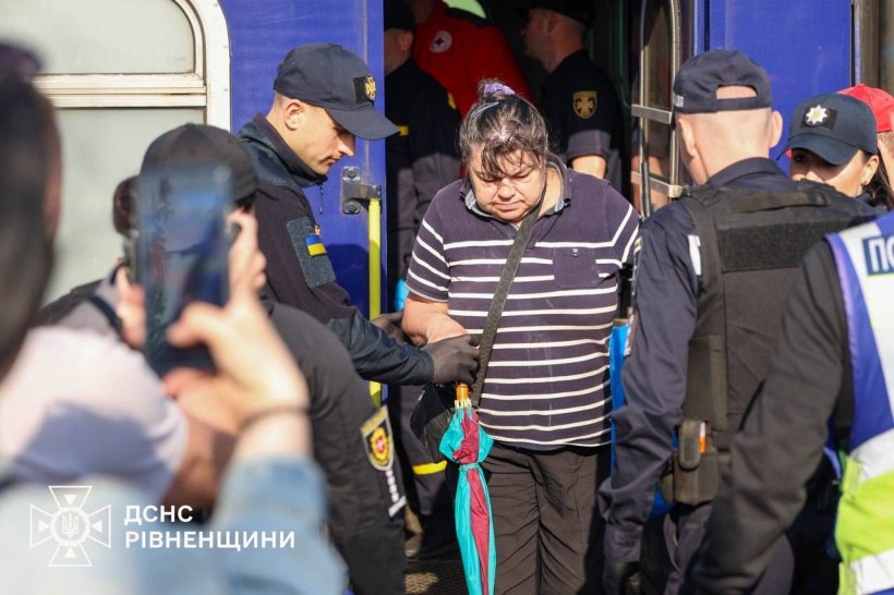 Рятувальники та волонтери допомагають жінці вийти з евакуаційного потяга