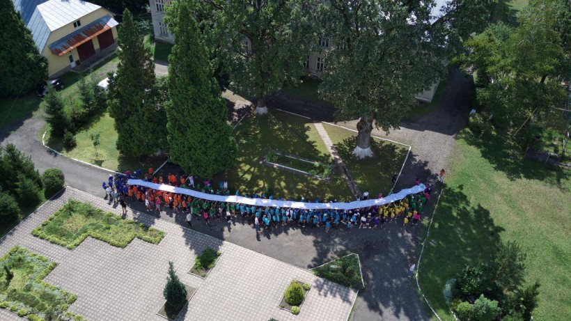 Діти тримають разом малюнки над головою.