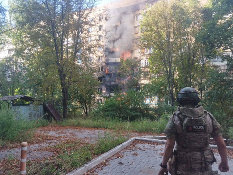 Пожежа в будинку, який пошкодили окупанти та правоохоронець, який стоїть поруч