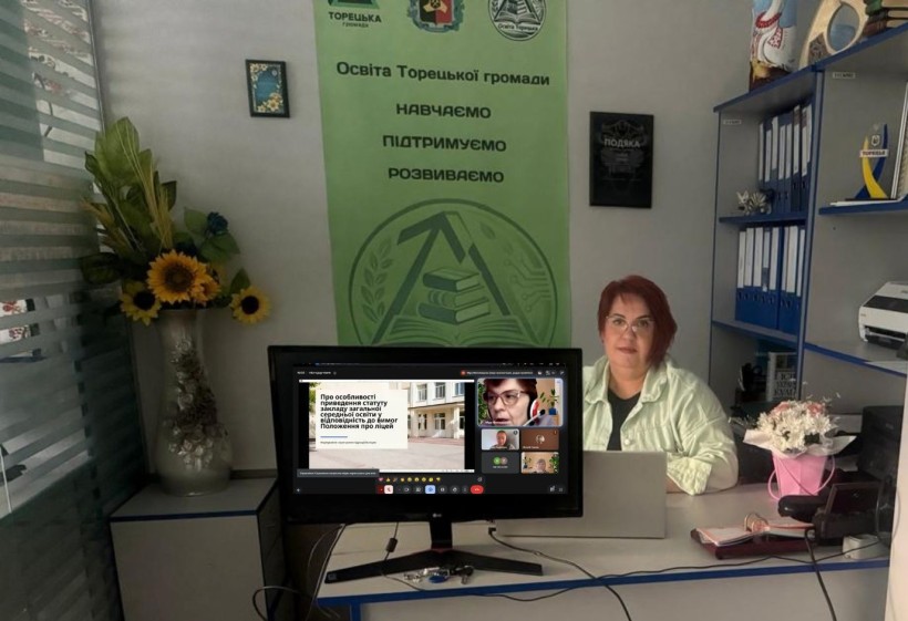 Представник військової адміністрації сидить за столом та слухає доповідача на семінарі
