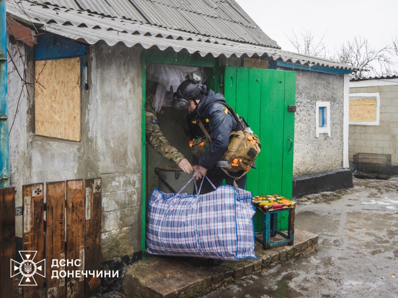 Рятувальник допомогає виносити речі з будинку.
