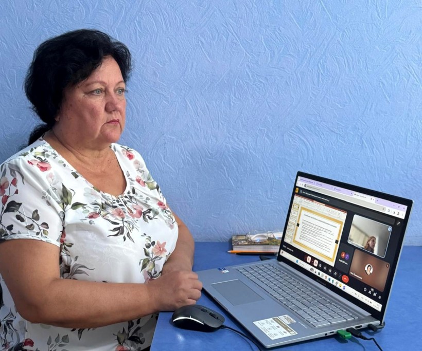 Представник військової адміністрації сидить за столом та слухає доповідача на семінарі