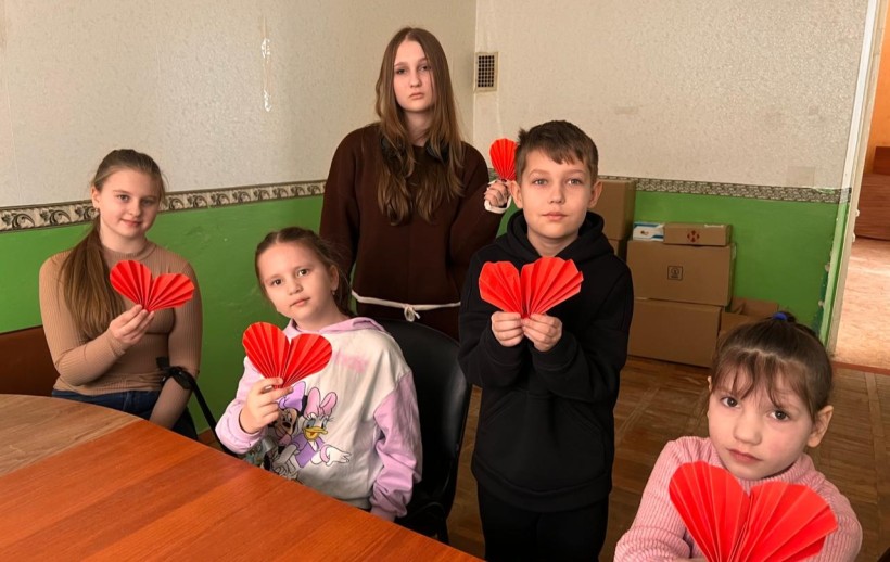 Діти тримають у руках зроблені власноруч червоні серця.